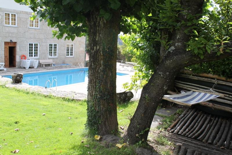dos árboles y un banco en un patio con piscina en Casa da Ribeira, en Alvoco da Serra