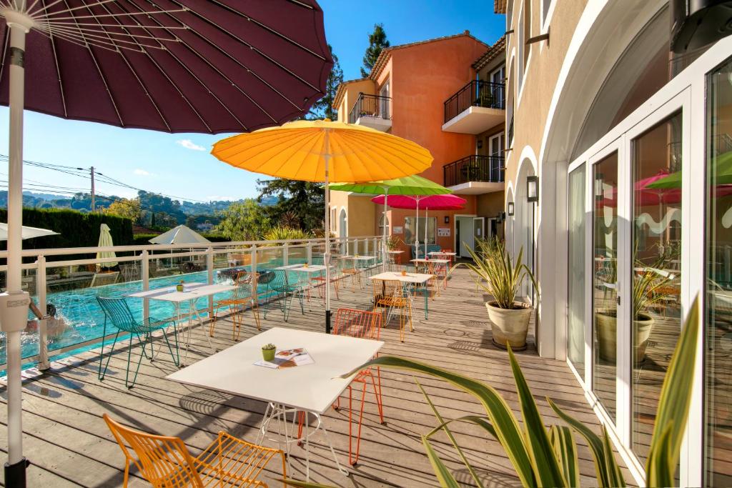 a patio with tables and umbrellas next to a pool at Privilège Appart-Hôtel Domaine De Mai - parking gratuit in Mougins