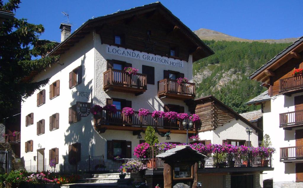 a white building with balconies and flowers on it at Hotel Locanda Grauson in Cogne