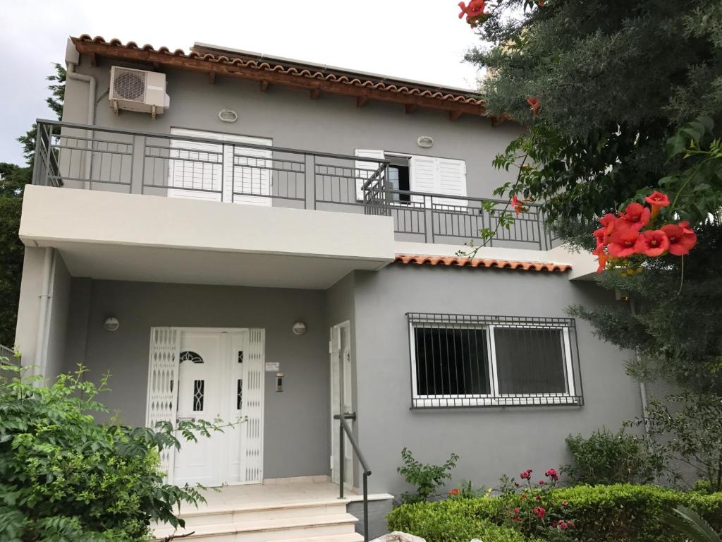 a white house with a balcony and red flowers at Loft near the beach in Loutraki