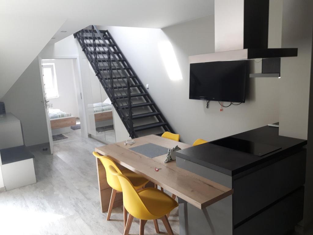 a kitchen and dining room with a wooden table and yellow chairs at Apartamenty Platinum in Łukęcin