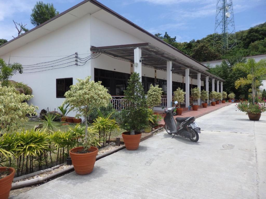 a scooter parked in front of a building with potted plants at Jamie's home with 2 bedrooms, can accommodate 6 guests in Ko Samed