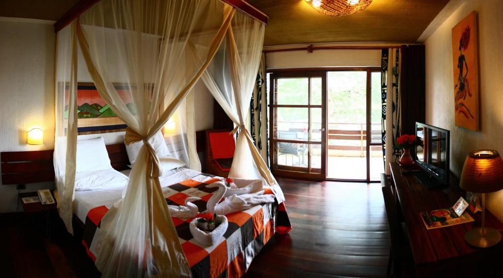 Schlafzimmer mit einem Bett mit Moskitonetzen in der Unterkunft Hotel Club du Lac Tanganyika in Bujumbura