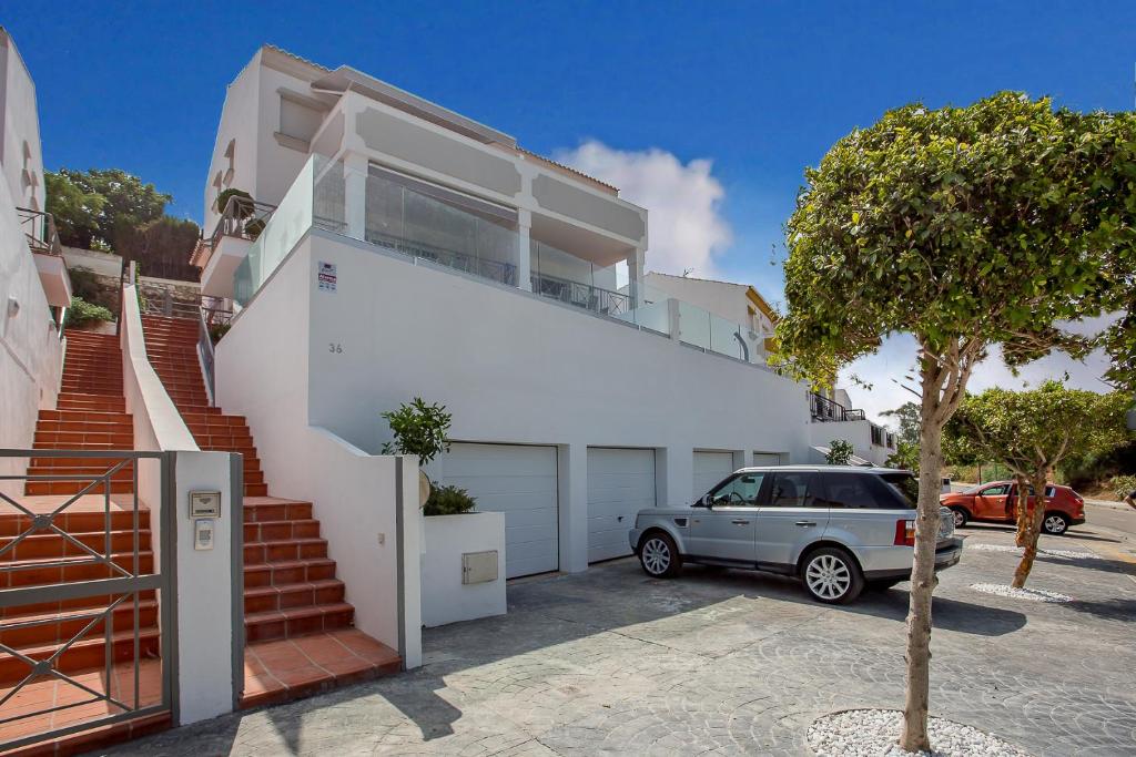 Biały dom z samochodem zaparkowanym przed nim w obiekcie Luxury Apartments with private swimming pool w Marbelli