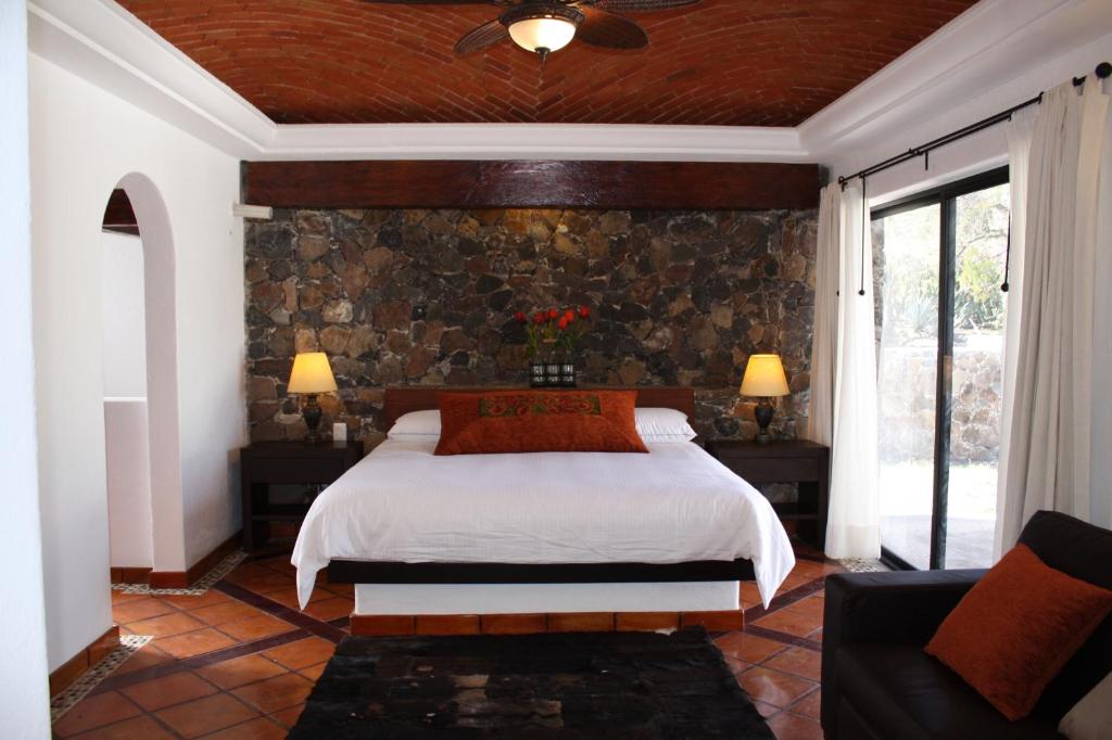 1 dormitorio con cama y pared de piedra en Hotel Villa Mexicana Golf & Equestrian Resort, en Villa del Pueblito