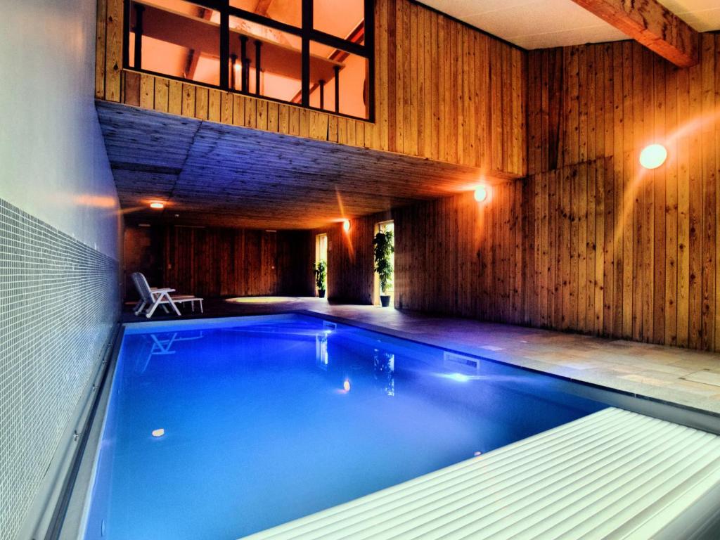 an indoor swimming pool in a building with a house at Holiday home with pool near park and ski area in Xhoffraix