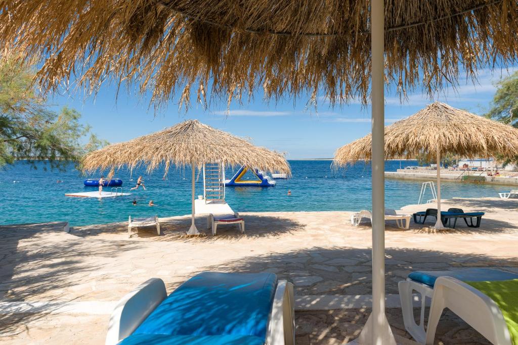 a beach with chairs and umbrellas and the water at Holiday Park Mandrice in Mandre
