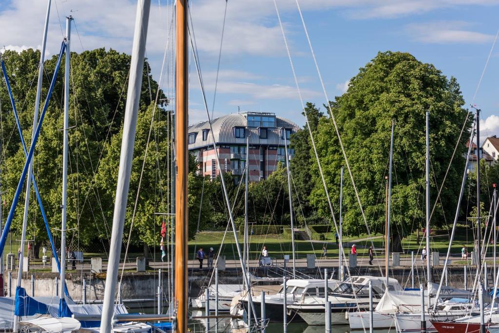 un grupo de barcos en un puerto deportivo con un edificio en el fondo en SEEhotel Friedrichshafen, en Friedrichshafen