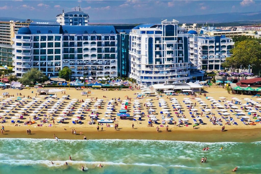 a beach with umbrellas and people in the water at Chaika Beach Resort in Sunny Beach