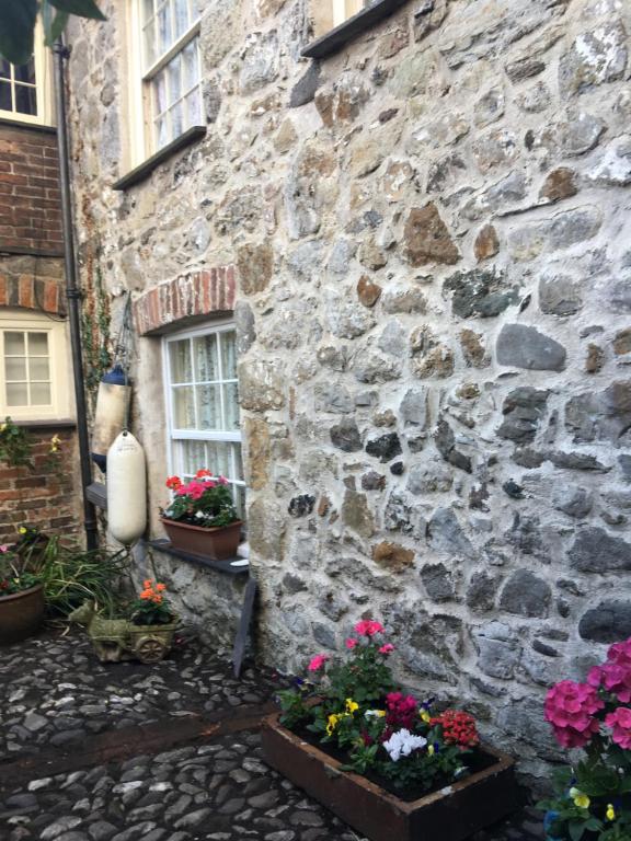 a stone building with flowers in front of it at Holiday Home Church Street in Beaumaris