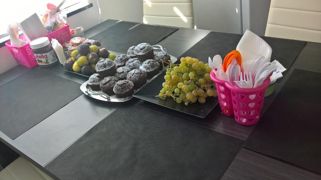 czarny stół z dwoma talerzami babeczek i owoców w obiekcie Quiero Más B&B w mieście San Nicola Arcella