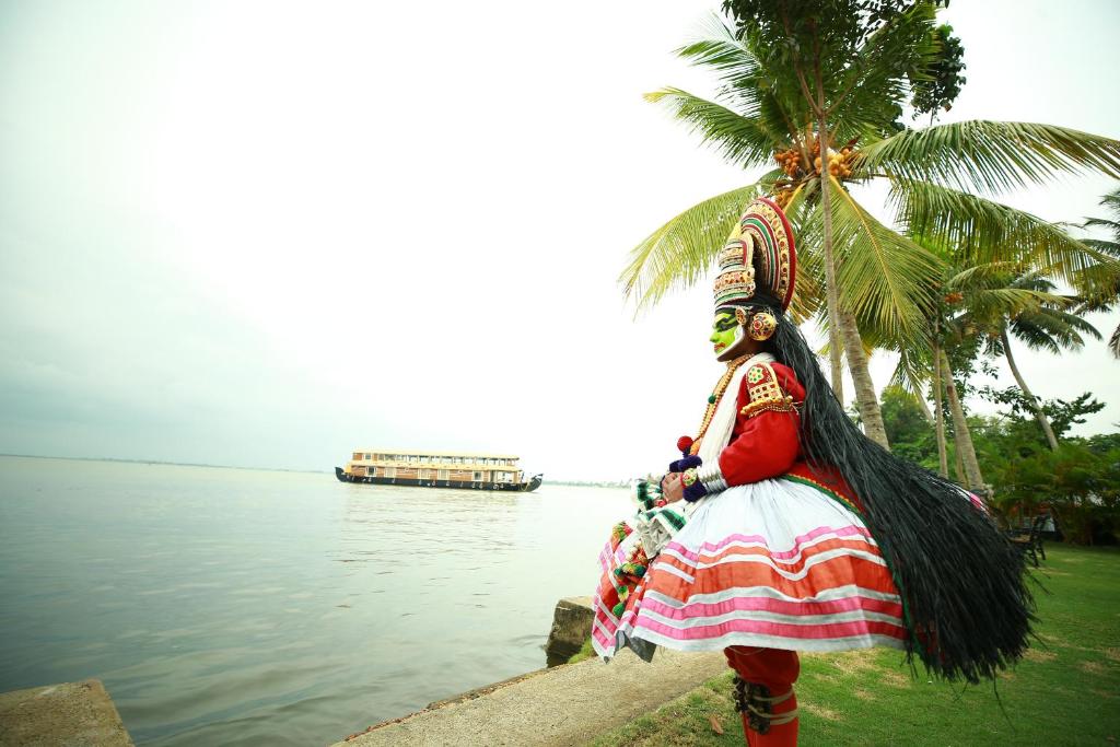 a woman in a dress standing next to a body of water at Southern Panorama Houseboats in Alleppey