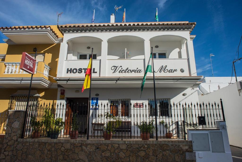 um edifício com duas bandeiras à frente em Hostal Victoria Mar em Chipiona