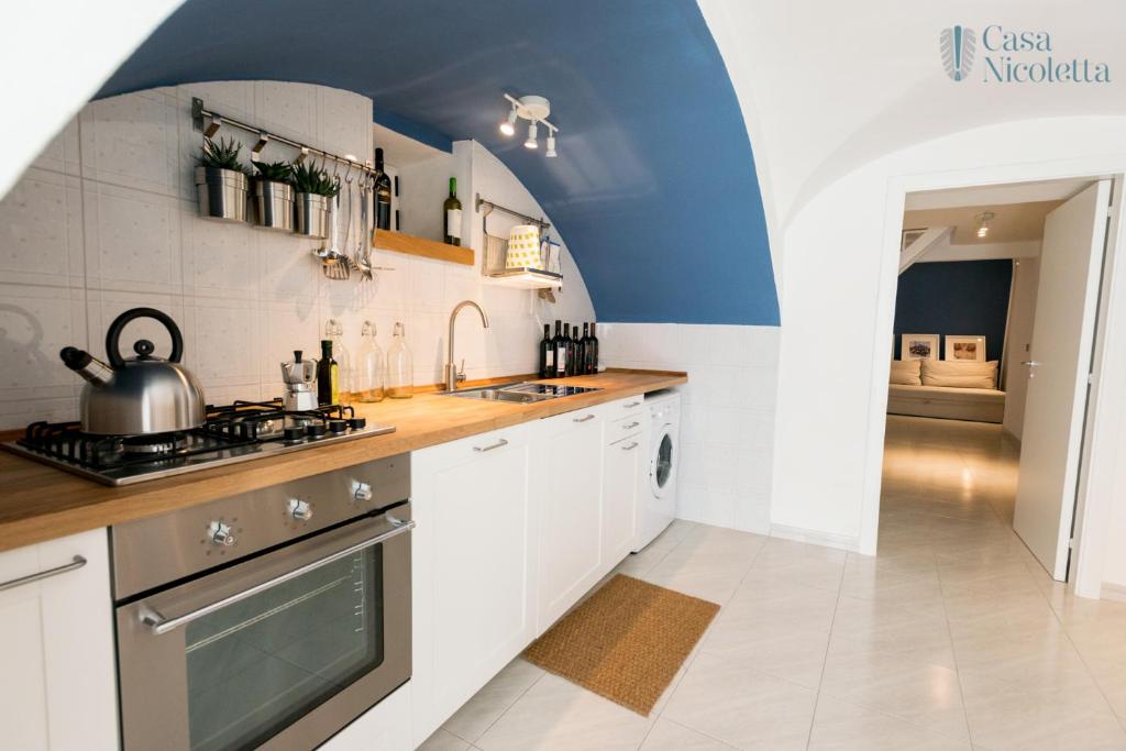 uma cozinha com armários brancos e um forno com placa de fogão em Casa Nicoletta em Noci