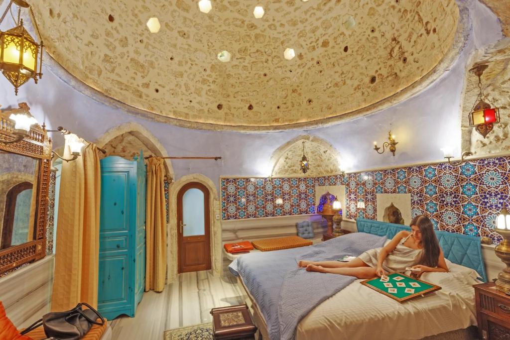 a woman sitting on a bed in a room with a ceiling at Hamam Oriental Suites in Rethymno Town