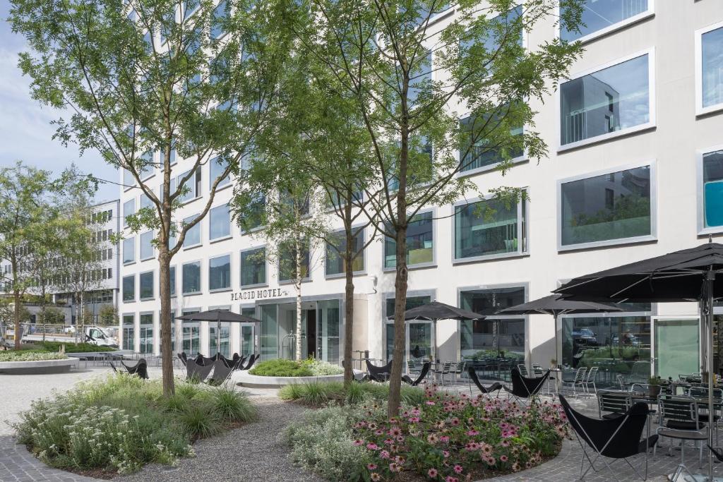 um edifício com mesas e guarda-chuvas à sua frente em Placid Hotel Design & Lifestyle Zurich em Zurique