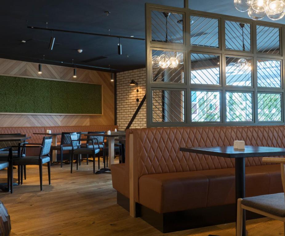 a restaurant with tables and chairs and windows at Pillo Hotel & Leisure Club in Ashbourne