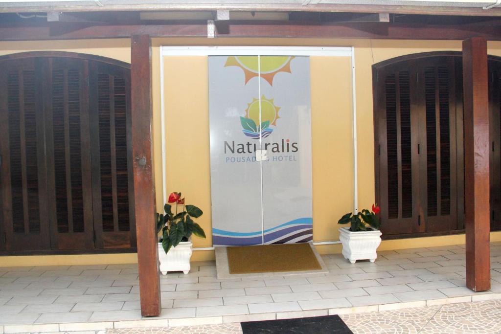 einer Eingangstür eines Gebäudes mit zwei Topfpflanzen in der Unterkunft Hotel Naturalis in Paranaguá