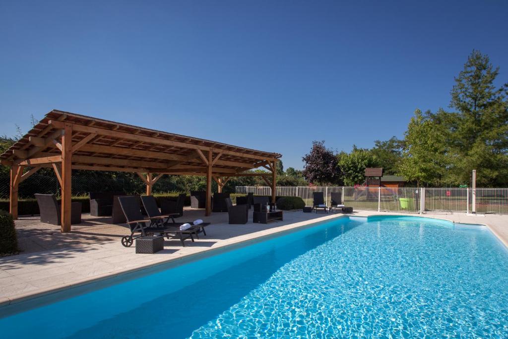 a swimming pool with a wooden pergola and a swimming poolvisor at Hôtel Carline Beaune in Beaune