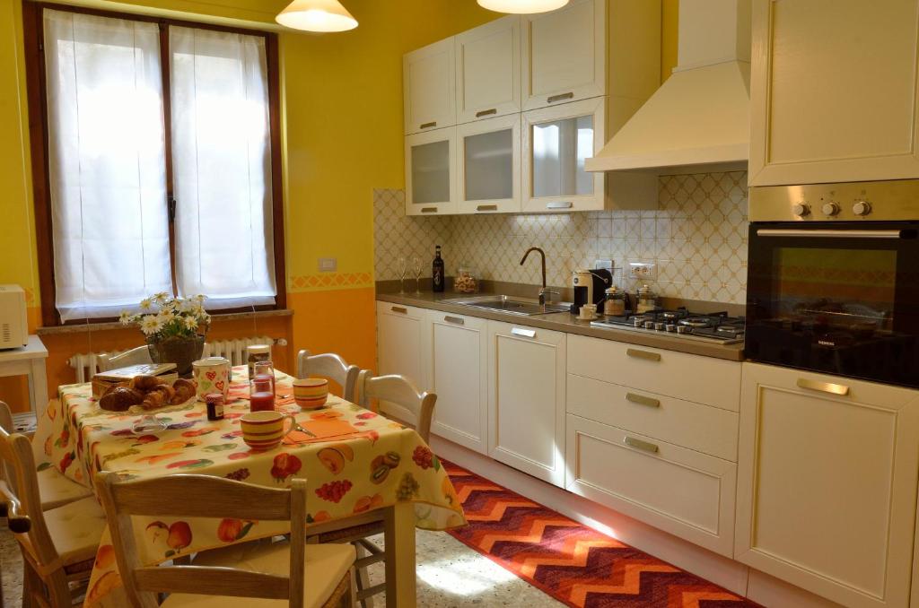 サン・カシャーノ・イン・ヴァル・ディ・ペーザにあるLa Casa di'Grilloのテーブル付きのキッチン、白いキャビネット付きのキッチン