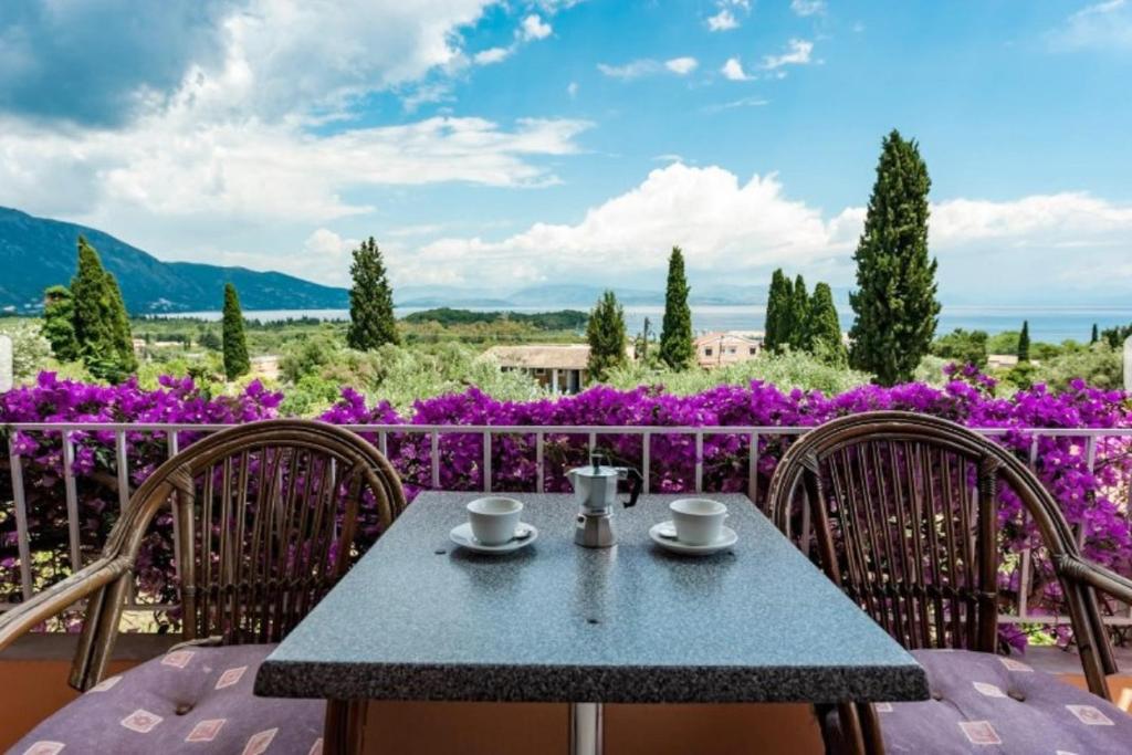 a table and chairs on a balcony with purple flowers at Marilena Apartments & Studios in Dassia