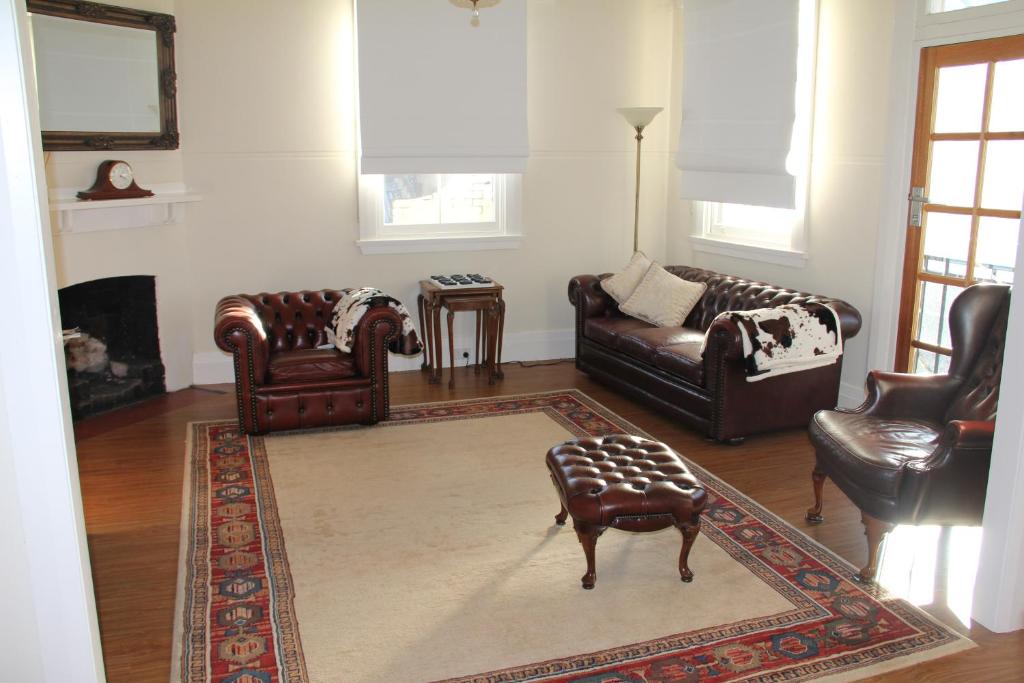 a living room with leather furniture and a rug at Mentor Chambers Apartment Bed & Breakfast in West Wyalong