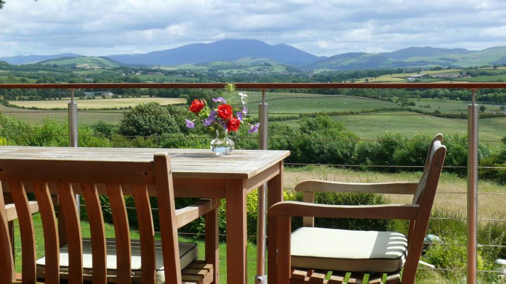 een tafel met stoelen en een vaas met bloemen op een balkon bij Westwood - The B&B with a view in Cockermouth