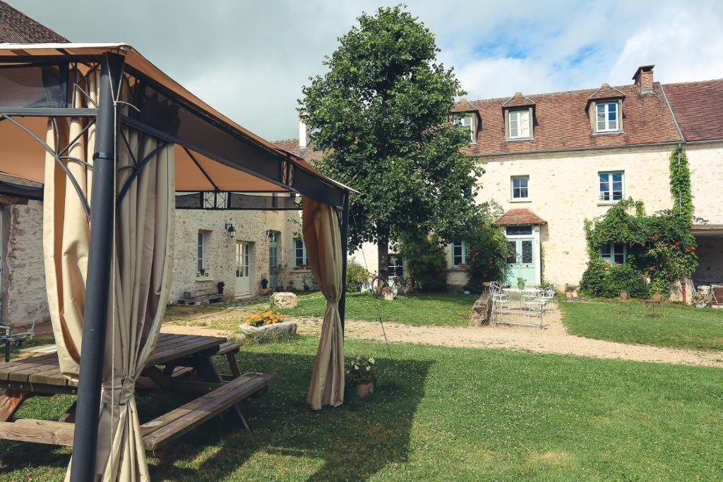 - un pavillon avec une table de pique-nique en face d'un bâtiment dans l'établissement La petite Ferme, à Chérence