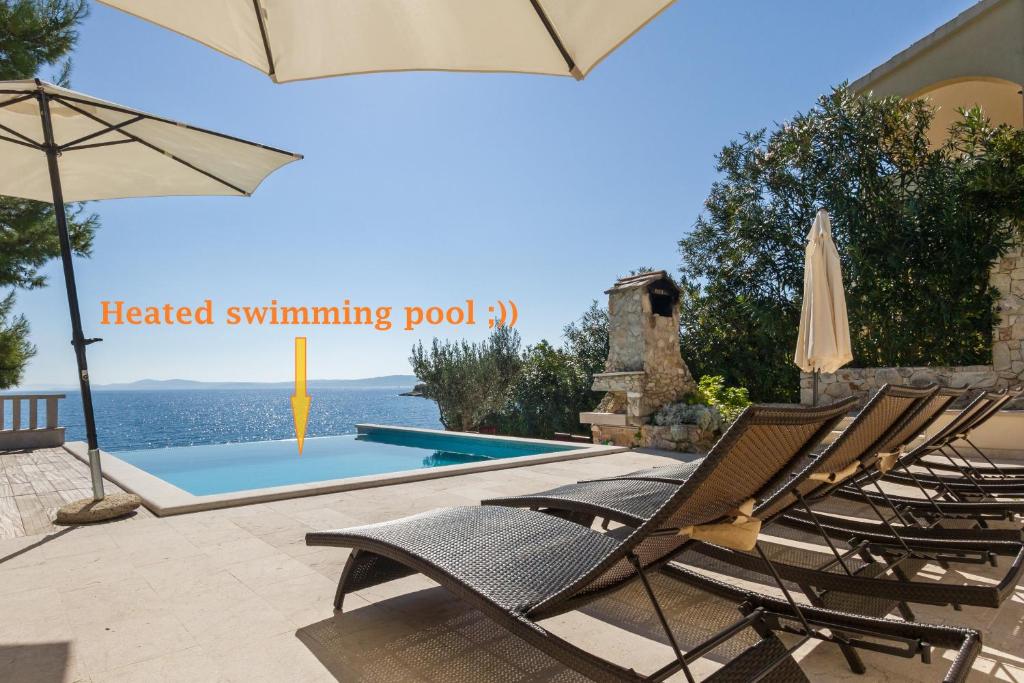 a pair of chairs and an umbrella next to a swimming pool at Apartments Villa Paula in Trogir
