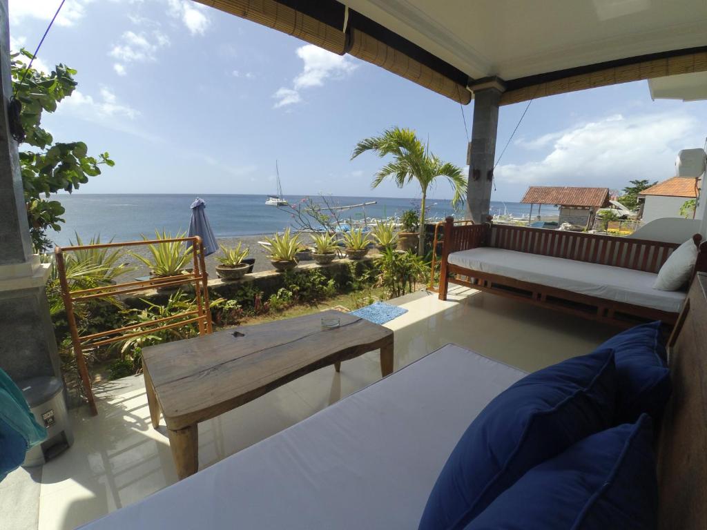 - un balcon avec un banc et une table donnant sur l'océan dans l'établissement The BBQ Guest House, à Amed