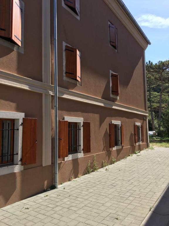 a building with brown doors and a sidewalk next to it at Apartments Porto Fianona in Plomin