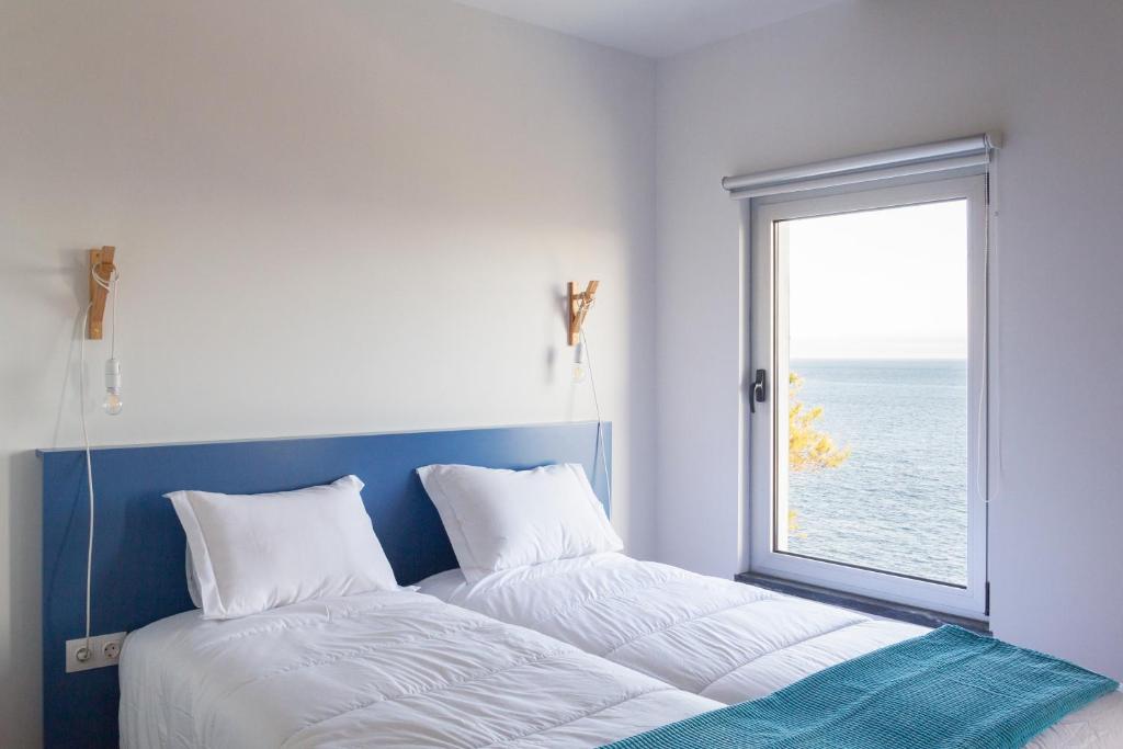 een slaapkamer met een groot bed en een raam bij Lofts Azul Pastel in Horta