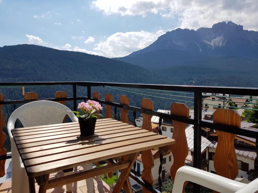 a wooden table on a balcony with a view of the mountains at Appartamento Comelico Dolomiti in Candide
