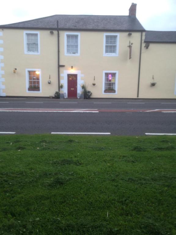 a white house with a red door on a street at Lynebank House Hotel, Bed & Breakfast in Carlisle