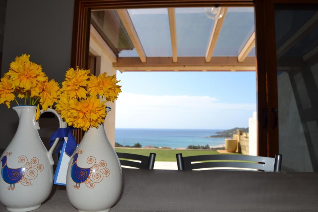 three white vases with yellow flowers sitting on a table at La Costa Est Villa con Vista Mare in Ogliastra Sardegna in Tertenìa