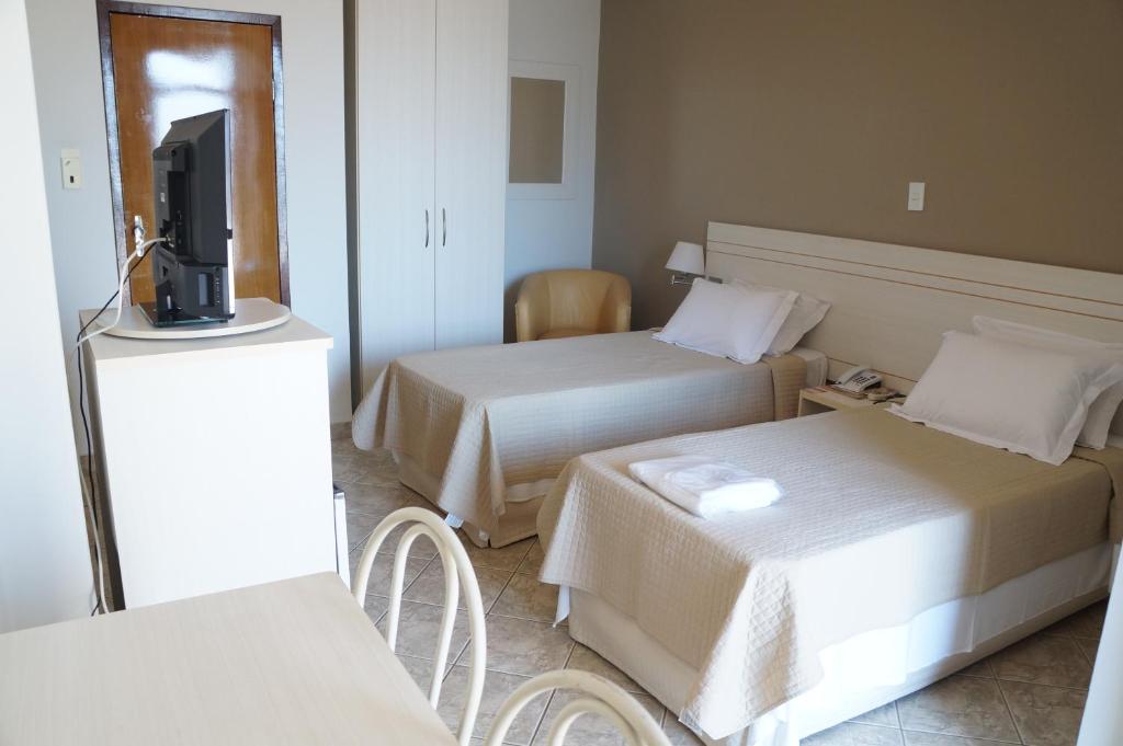 a hotel room with two beds and a flat screen tv at Manhuaçu Center Hotel in Manhuaçu