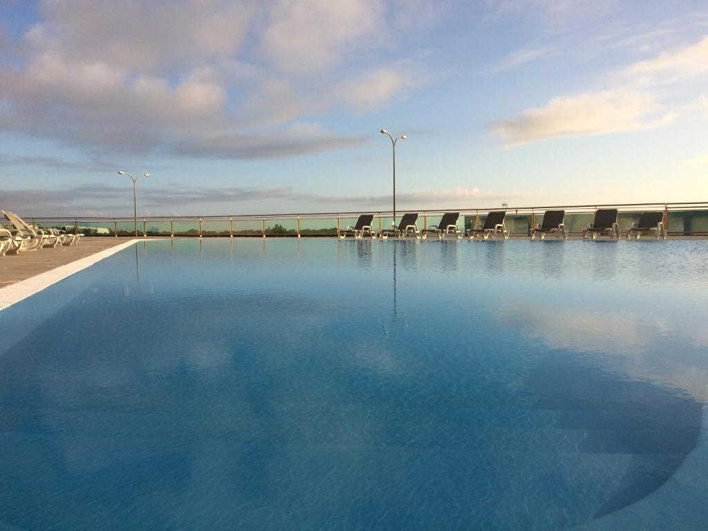 ein großer Pool mit blauem Wasser neben einer Brücke in der Unterkunft Ericeira Surf and Sun in Ericeira
