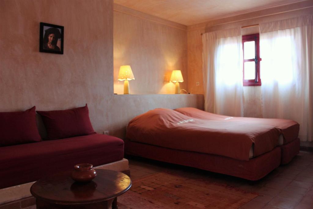 a hotel room with a bed and a couch at Hotel De Charme Les 3 Chameaux 4 étoiles in Mirleft