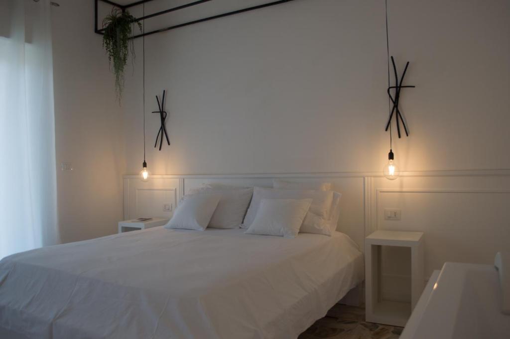 um quarto com uma cama branca com 2 mesas e luzes em Boite d'Esprit b&b de luxe em Rossano Stazione