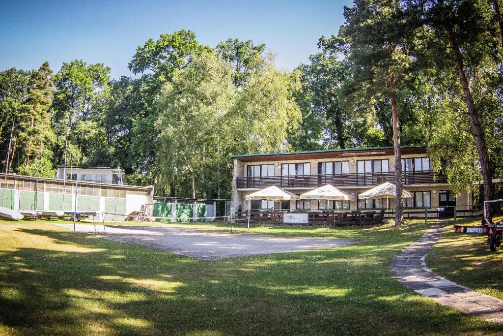 a building in a park with trees in the background at Yacht Club Bezdrev in Hluboká nad Vltavou