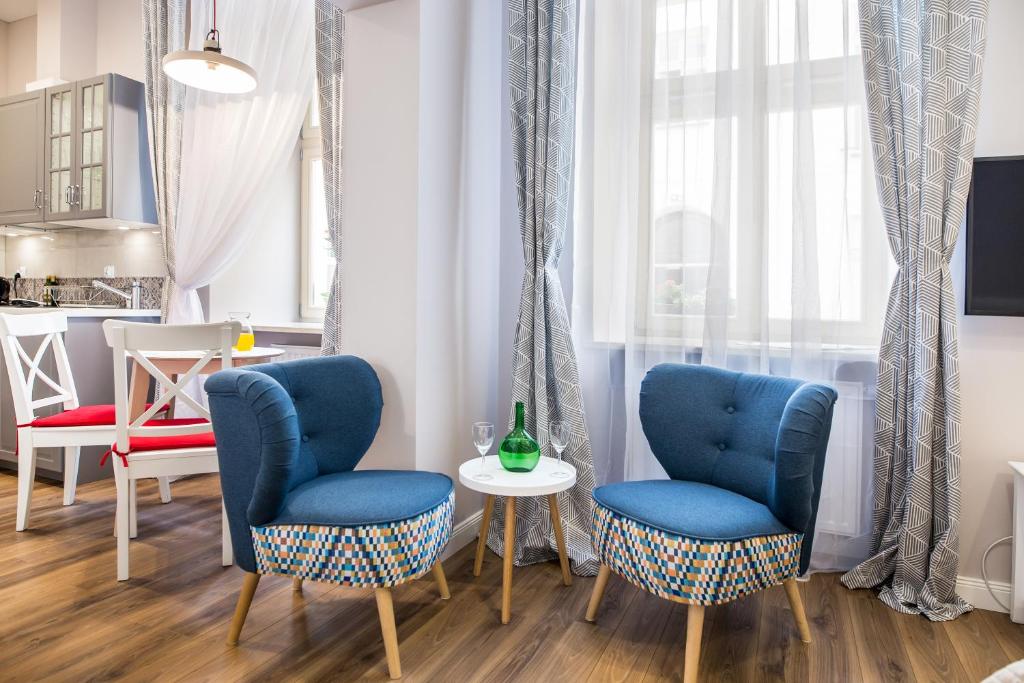 Sitting nook with two blue patterned chairs, small table with bottle and glasses, bright window.