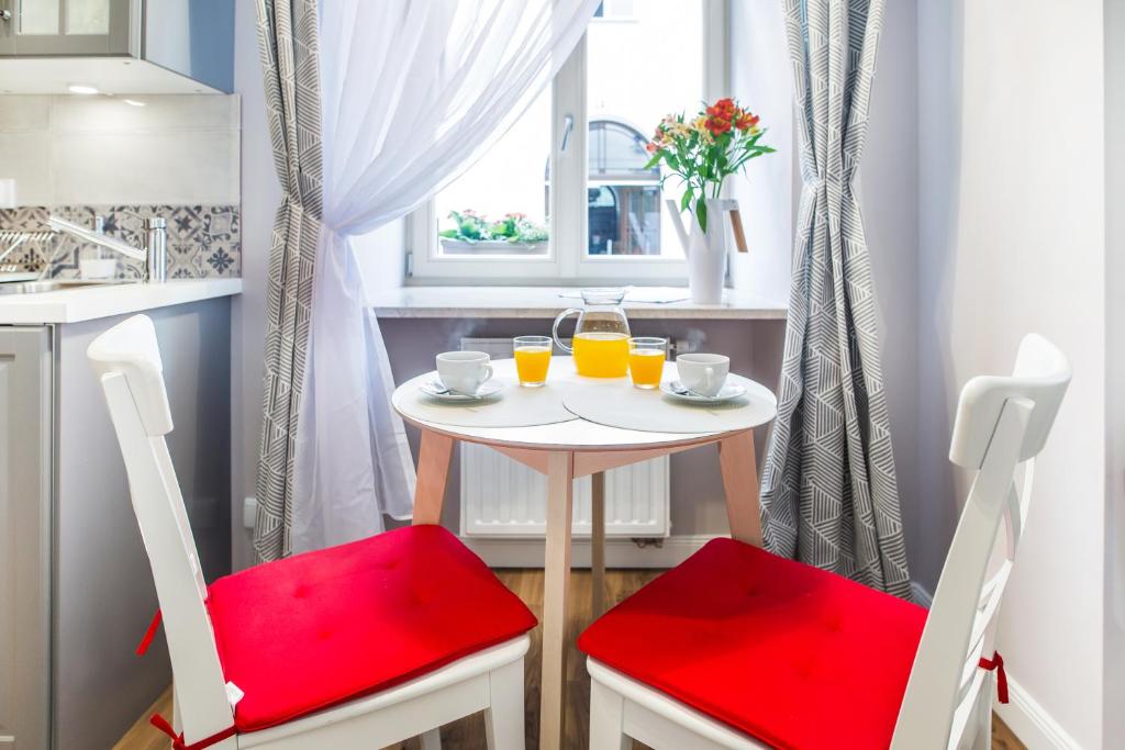 Breakfast nook with round table, two white chairs with red cushions, pitcher of orange juice.