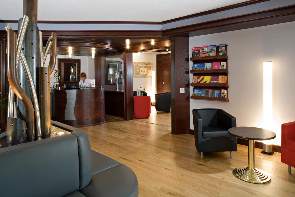 a lobby with a chair and a bar in the background at Cottage Logis Hôtel - Restaurant in Dudelange