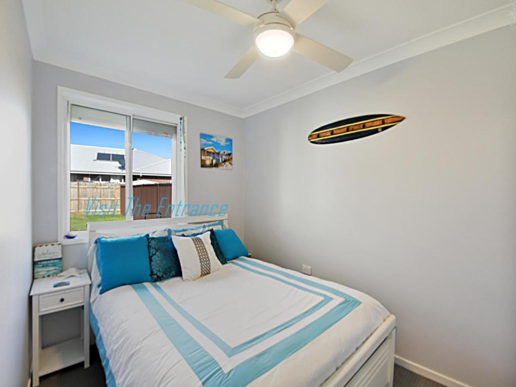 a bedroom with a bed and a ceiling fan at The Nautical House in The Entrance
