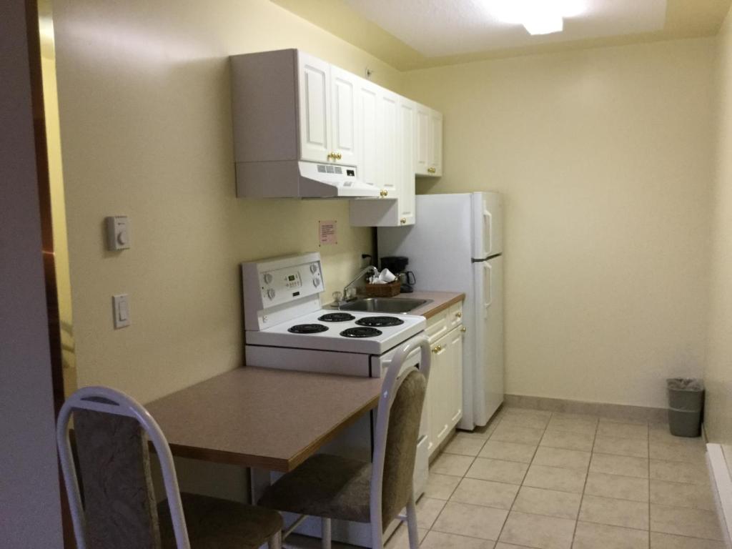a small kitchen with a stove and a refrigerator at Western Budget Motel #1 Grande Prairie in Grande Prairie