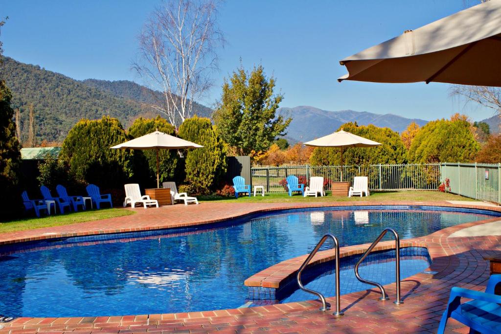 a swimming pool with chairs and umbrellas at Discovery Parks - Bright in Bright