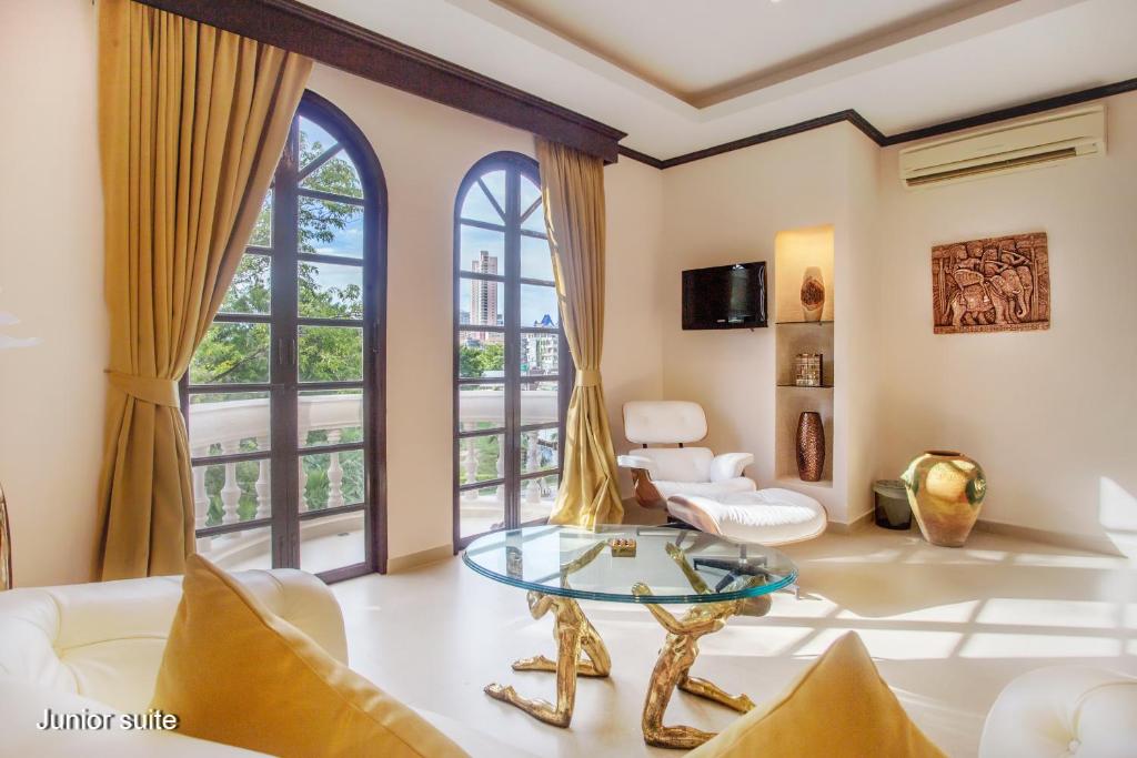 a living room with a glass table and windows at Poseidon Boutique Hotel in Pattaya South