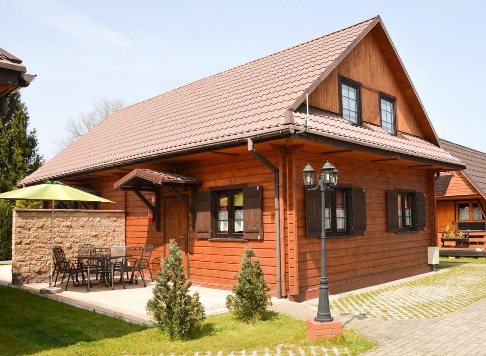 una pequeña casa de madera con mesa y sillas en Domki DUET en Dźwirzyno