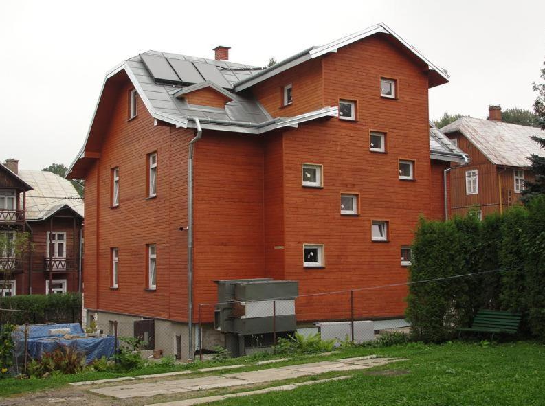 ein großes braunes Gebäude mit einem Metalldach in der Unterkunft Hostel Promyk in Iwonicz-Zdrój