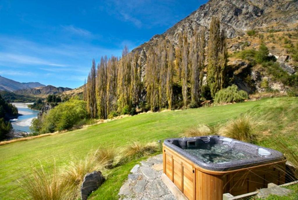 un bain à remous installé au sommet d'une colline herbeuse dans l'établissement The Canyons B&B, à Queenstown